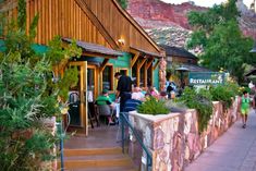 people are walking down the steps to an outdoor restaurant in front of a mountain range