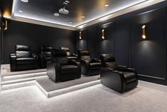 a home theater with black leather chairs and white carpeted steps leading up to the ceiling