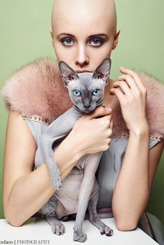 a woman holding a cat in her arms with an odd look on her face and hair