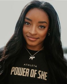 a woman with long hair wearing a black t - shirt and smiling at the camera