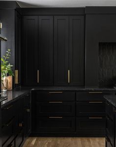 a kitchen with black cabinets and gold trim on the counter tops, along with wooden flooring