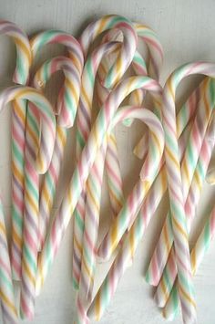 several candy canes are lined up on a white surface, one is green and the other is pink