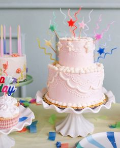 a birthday cake and cupcakes on a table with confetti streamers