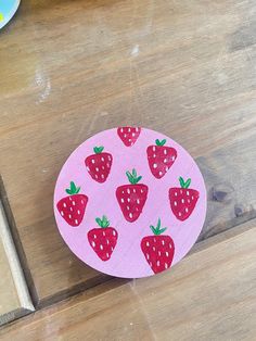 a pink sticker with strawberries on it sitting on a wooden table next to a box