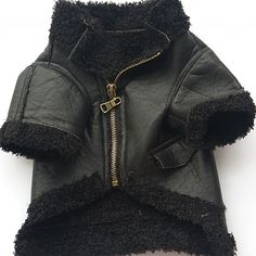 a black jacket with a zipper on the front and collar is sitting on a white surface