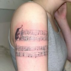 a woman with a tattoo on her arm that has music notes and an apple in it