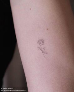 a single rose tattoo on the left side of the arm, with one flower in it's center