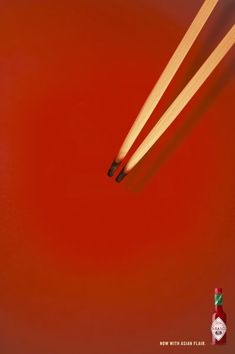 three chopsticks sticking out of a red background with a bottle of ketchup in the foreground