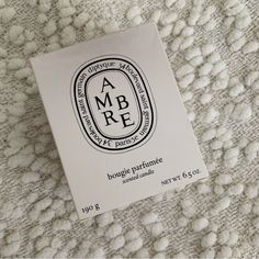 the label for an ambre cosmetics product on a white surface with small balls of yarn in the background