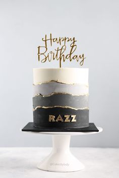 a black and white birthday cake with gold lettering on top that says happy birthday raz