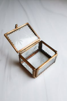 an open jewelry box sitting on top of a white table next to a wall mounted mirror