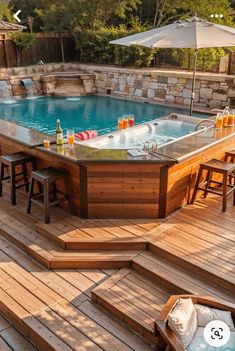 an outdoor hot tub with seating and umbrellas on the deck next to it is surrounded by wooden steps