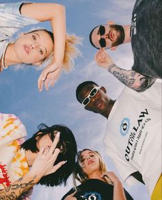 a group of people standing in a circle looking up at the sky with their hands together