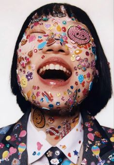 a woman with her mouth open covered in buttons and confetti on her face