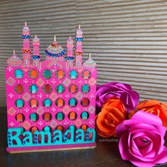 there is a pink birthday cake with candles on it and flowers in the foreground