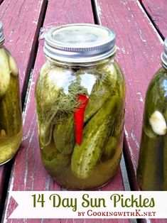 three jars filled with pickles sitting on top of a wooden table