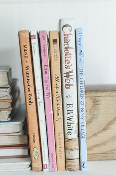 a stack of books sitting on top of a white shelf next to a wooden box