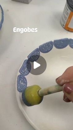 someone is painting a plate with blue circles on it