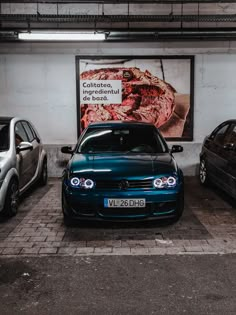 three cars parked next to each other in front of a large poster on the wall