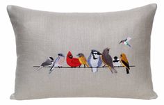 the birds are sitting on the wire embroidered onto the pillow cover, which is made from linen