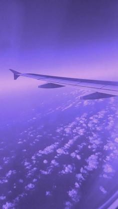 the wing of an airplane flying in the sky with clouds and blue skies above it