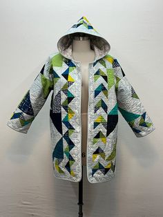 a mannequin wearing a jacket made from quilts and fabrics on a dummy