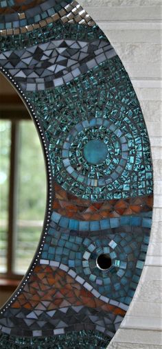 a circular mirror made out of mosaic tiles