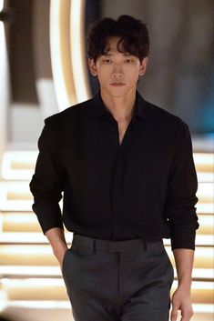 a man in black shirt and pants walking down a runway with his hands on his hips