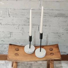 two white candles sitting on top of a wooden table next to some black and white circles