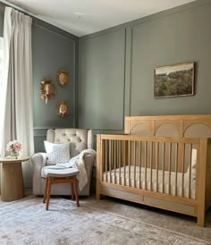 a baby's room with a crib, chair and ottoman