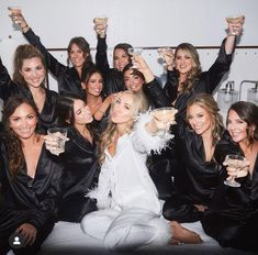 a group of beautiful women sitting next to each other holding wine glasses in their hands