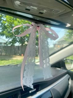 the interior of a car decorated with pink ribbon and lace, hanging from the dash board