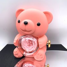 a pink teddy bear holding a rose in its mouth