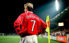 a man standing on top of a soccer field wearing a red jacket and white pants