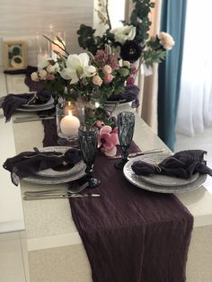 the table is set with plates, silverware and flowers