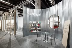 an exhibit booth with chairs and tables in front of a circular metal wall that reads hungry