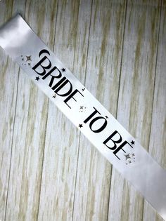 a bride to be sash with stars on it sitting on a wooden table next to a knife