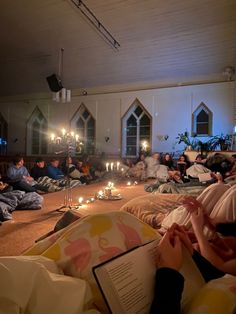 people are sitting on the floor with candles in front of them and one person is reading