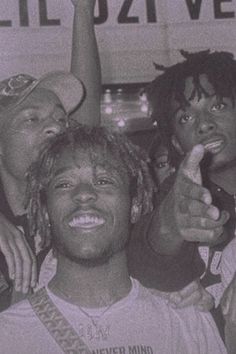 three young men standing next to each other in front of a sign and pointing at the camera