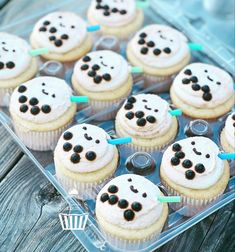 cupcakes with white frosting and black dots on them in a plastic container