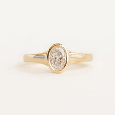 a yellow gold engagement ring with a single round diamond in the center, on a white background