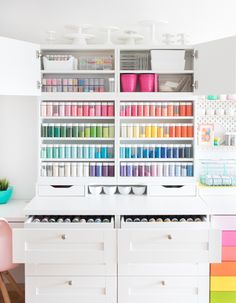 an organized craft room with white drawers and lots of colorful items on the shelves, including crayons