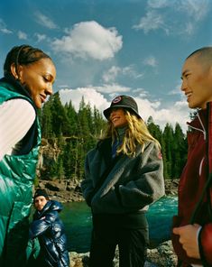 three women standing next to each other near water