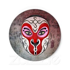 a red and white mask is on the side of a metal plate with an ornate design