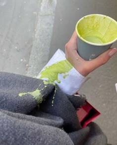 a person holding a cup with green paint on it