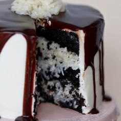 a close up of a cake with chocolate icing and coconut on the top slice