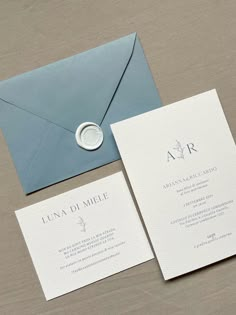 an envelope with a wax stamp on it next to two cards and a ring in the middle