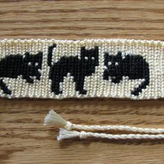 two pieces of beaded fabric with black cats on them, one is white and the other is black