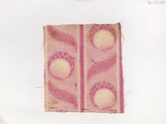 a piece of cloth with pink and white designs on the side, in front of a white background