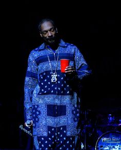 a man with a red cup in his hand standing next to a drum and drums